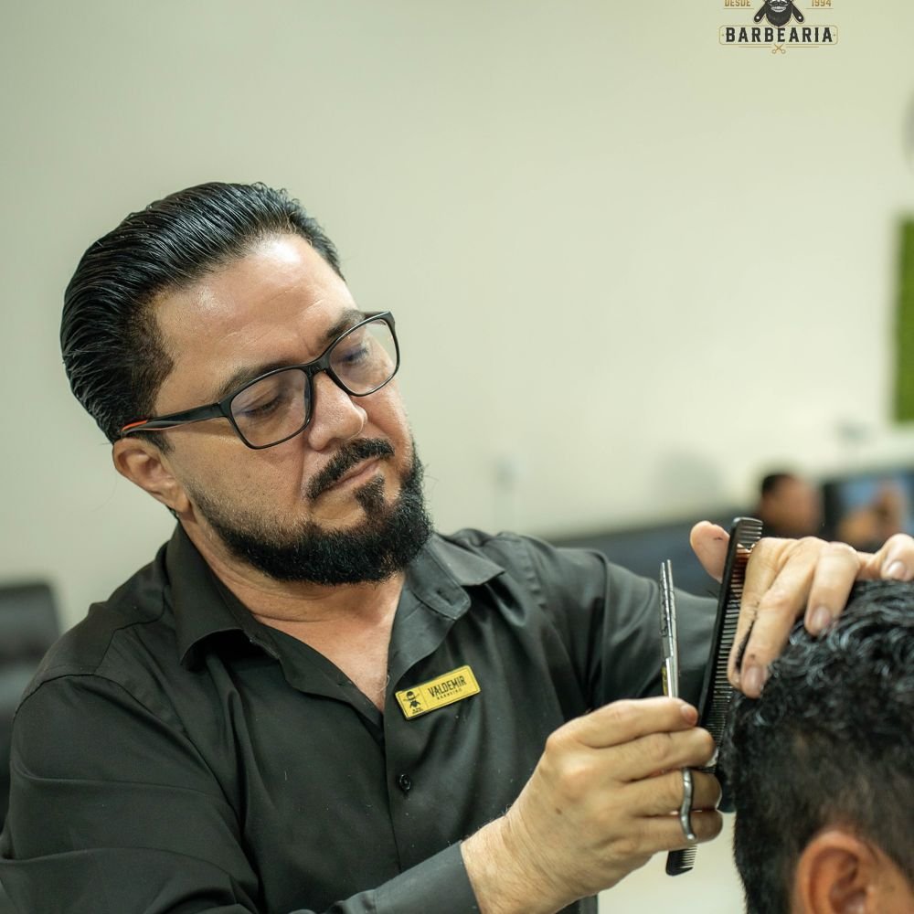 Veras cortando o cabelo de um cliente na tesoura