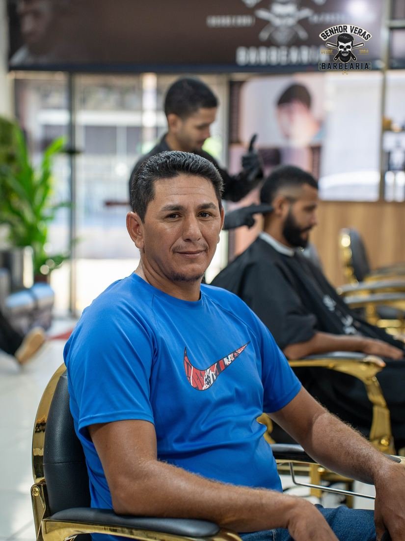 Cliente sentado na cadeira dourada da barbearia